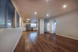 Unfurnished living room featuring dark wood-type flooring and recessed lighting