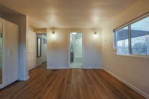 Unfurnished bedroom featuring dark wood-style floors and connected bathroom