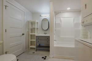 Full bath featuring vanity, bathing tub / shower combination, stacked washer / drying machine, and light tile patterned floors