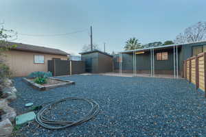 Fenced backyard featuring a vegetable garden, a patio area, and a shed