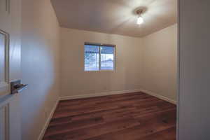 Unfurnished room featuring dark wood-style flooring and baseboards