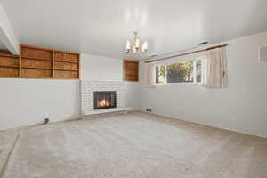 Family room with carpet, built in shelves, a brick fireplace, and hanging lights
