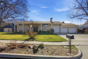 View of front of home featuring an attached garage, a chimney, brick siding, driveway, and covered porch