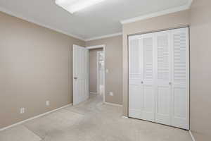 Bedroom with light carpet, crown molding, and a closet