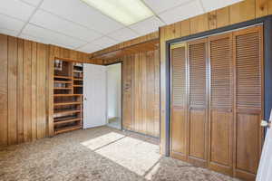 Bedroom featuring paneled walls, light colored carpet, and a closet