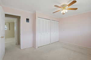 Bedroom featuring crown molding, light colored carpet, two closets, and a ceiling fan