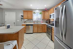 Kitchen featuring stainless steel appliances, light countertops, wood finish cabinetry, and recessed lighting