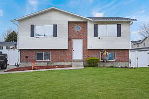 Raised ranch with a gate, entry steps, and brick siding