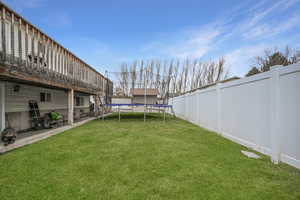 View of grassy yard with a trampoline