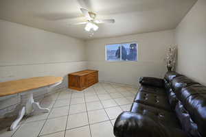 Living room with a ceiling fan and light tile patterned flooring