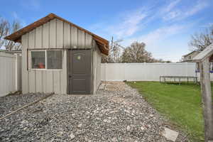View of shed with a trampoline and a fenced backyard