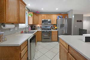 Kitchen featuring stainless steel appliances, light countertops, and wood finish cabinets
