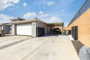 View of front facade featuring a garage, concrete driveway, and stucco siding