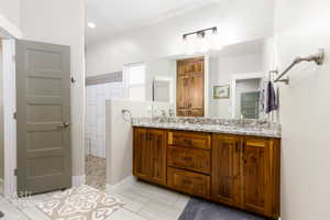 Full bathroom featuring double vanity, walk in shower, and light tile patterned floors