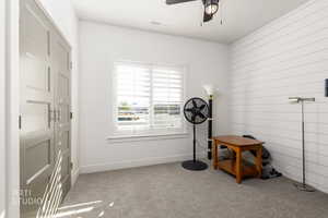 Miscellaneous room featuring light carpet, wooden walls, and ceiling fan