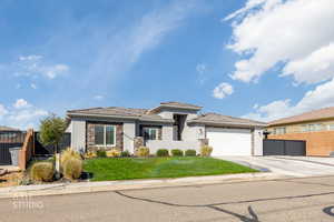 Prairie-style home with an attached garage, concrete driveway, stone siding, stucco siding, and a gate