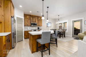 Kitchen featuring wood finish cabinets, a kitchen island with sink, a breakfast bar area, and light wood finished floors