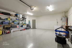 Garage featuring strapped water heater, fridge, and a garage door opener