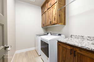 Laundry area with cabinet space, light wood-type flooring, and washer and clothes dryer
