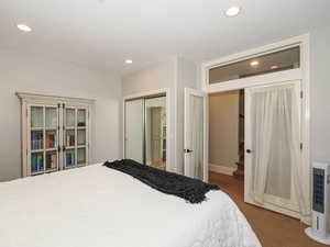 Bedroom with a closet, dark carpet, and recessed lighting