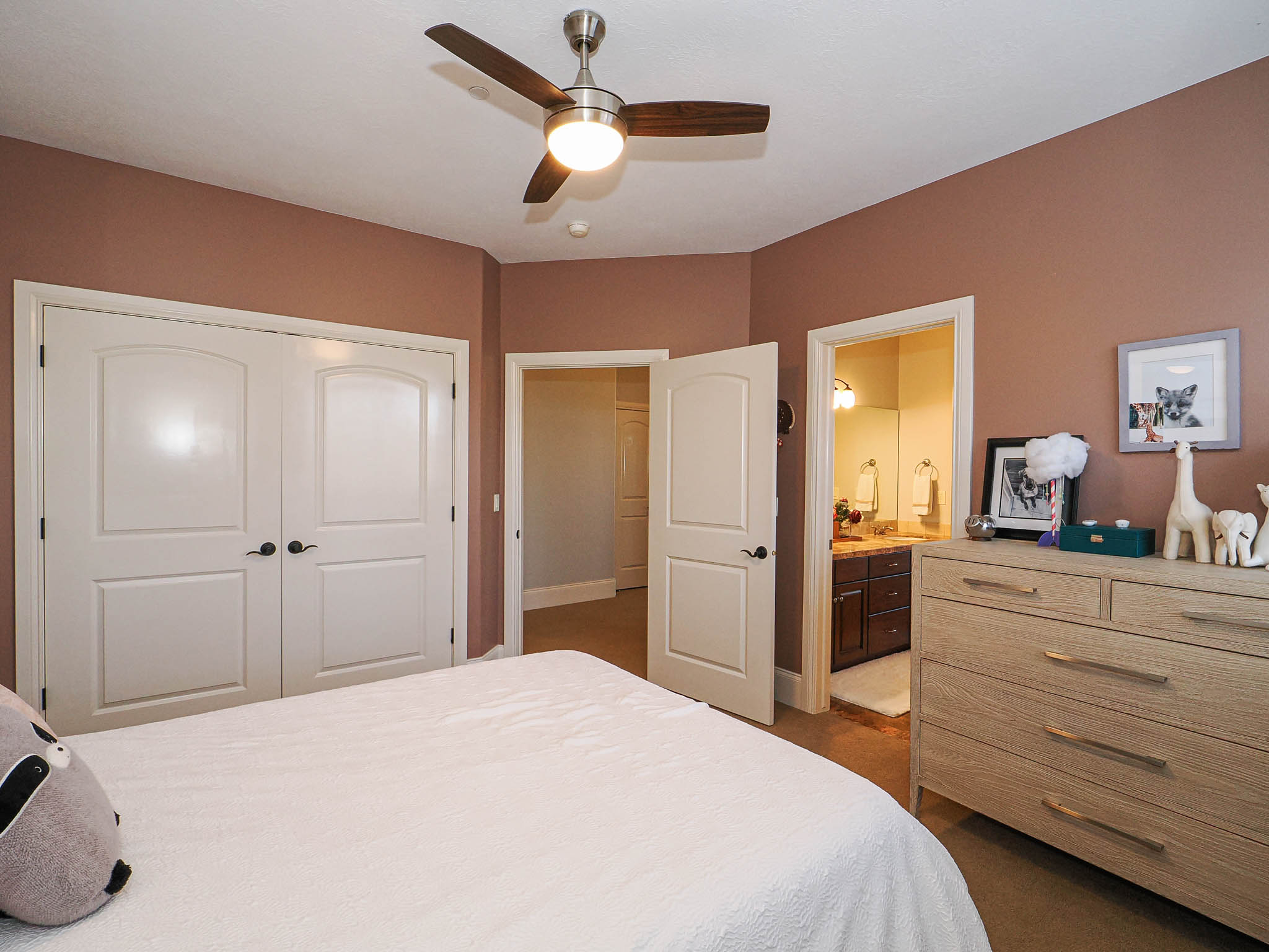 Bedroom with dark colored carpet, a ceiling fan, a closet, and ensuite bathroom