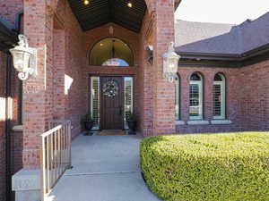 Property entrance with brick siding, roof with shingles, and a patio area