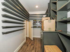 Walk in closet with dark wood-type flooring