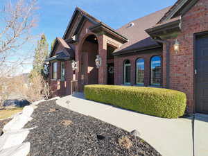 View of front facade featuring brick siding and roof with shingles