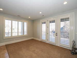 Empty room featuring plenty of natural light, recessed lighting, carpet, and french doors