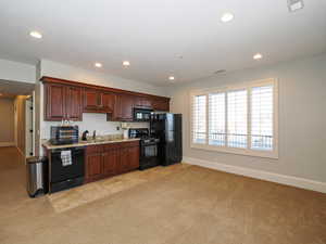 Kitchen featuring light carpet, black appliances, recessed lighting, and light stone counters