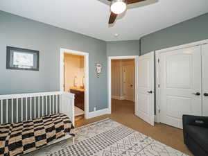 Bedroom with light colored carpet, connected bathroom, a closet, and ceiling fan