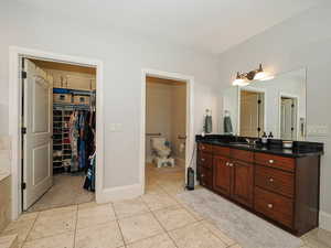 Bathroom with vanity, light tile patterned floors, and a walk in closet