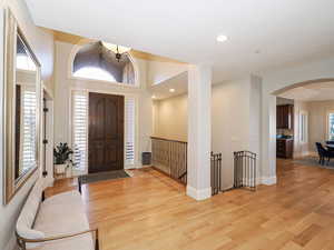 Entrance foyer featuring light wood finished floors, arched walkways, recessed lighting, and a high ceiling