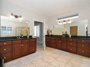 Full bath featuring a stall shower, two vanities, and light tile patterned floors