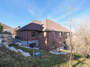 Back of house featuring brick siding and a shingled roof