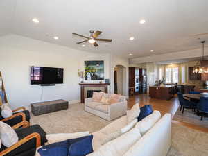 Living area featuring a fireplace, a chandelier, ceiling fan, arched walkways, and light wood-style floors