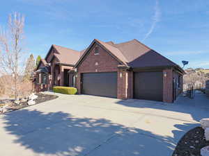 View of front of house featuring an attached garage, brick siding, concrete driveway, and roof with shingles