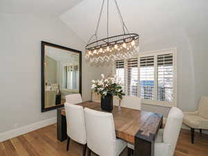 Dining space featuring wood finished floors, vaulted ceiling, and suspended lighting