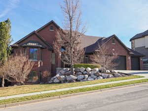 View of front of property with brick siding, an attached garage, driveway, and a front lawn