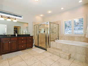 Bathroom with a walk in closet, a stall shower, a bath, vanity, and light tile patterned floors