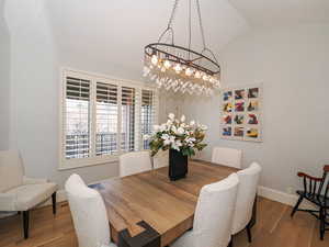 Dining area featuring wood finished floors, vaulted ceiling, and a chandelier