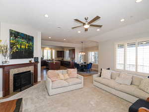 Living room with a ceiling fan, plenty of natural light, a tile fireplace, and hanging lights