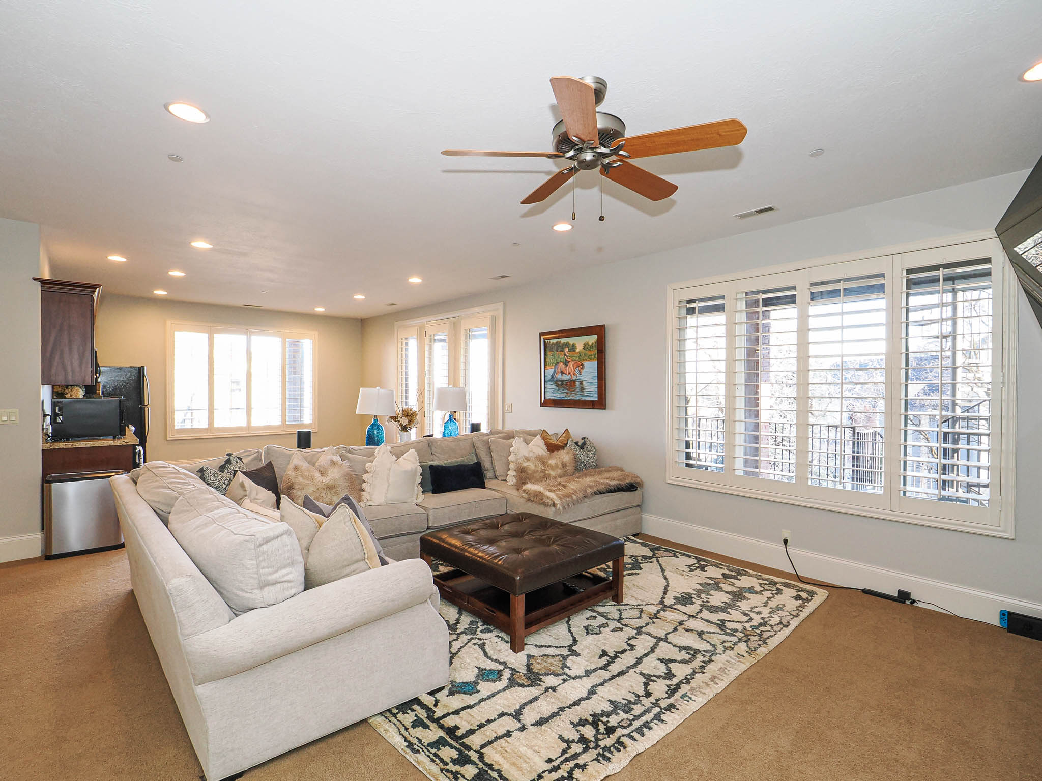Carpeted living room with ceiling fan and recessed lighting