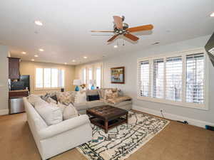 Carpeted living room with ceiling fan and recessed lighting