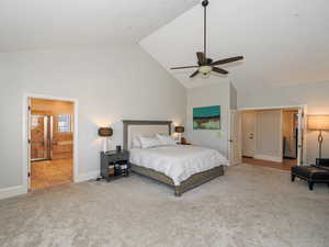 Bedroom with light colored carpet, ensuite bathroom, ceiling fan, and a high ceiling