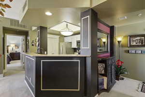 Kitchen featuring light colored carpet, white cabinetry, light stone countertops, stainless steel appliances, and a peninsula
