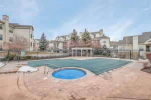 Community pool featuring a hot tub, a patio area, a residential view, and a pergola