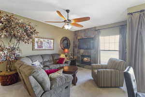 Living area with carpet floors, a ceiling fan, and a tile fireplace