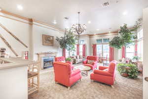 Living area featuring a high end fireplace, light colored carpet, hanging lights, and crown molding