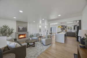 Living area with light wood-style flooring, recessed lighting, and a lit fireplace